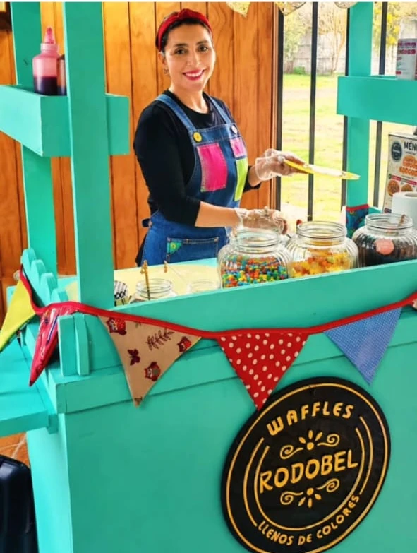 Integrante del equipo Rodobel atendiendo su carrito de waffles turquesa